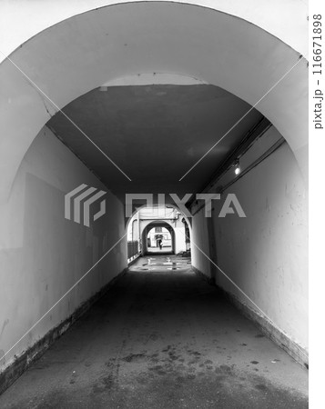 Black and white tunnel view with arches and person in distance 116671898