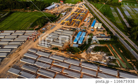 Aerial view of a new road development or highway under construction. Top view from a drone over road construction workers amidst mountains. Construction Site with Cranes and Heavy Equipment. Aerial view of a new road development or highway under construction. Top view from a drone over road construction workers amidst mountains. Construction Site with Cranes and Heavy Equipment. 116675938