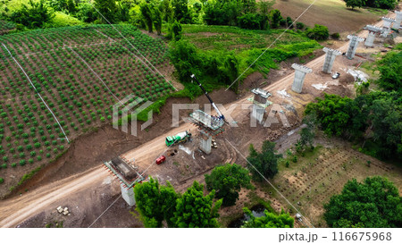 Aerial view of a new road development or highway under construction. Top view from a drone over road construction workers amidst mountains. Construction Site with Cranes and Heavy Equipment. Aerial view of a new road development or highway under construction. Top view from a drone over road construction workers amidst mountains. Construction Site with Cranes and Heavy Equipment. 116675968