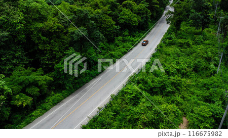 Aerial view of countryside asphalt road with car and green forest. Drive on the road between green forests. Aerial view of countryside asphalt road with car and green forest. Drive on the road between green forests. 116675982
