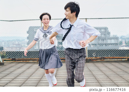 屋上で一緒に駆ける高校生男女 116677416