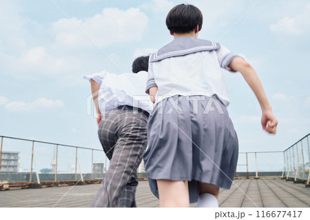 屋上で一緒に駆ける高校生男女 116677417