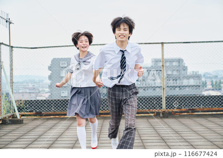 屋上で一緒に駆ける高校生男女 116677424