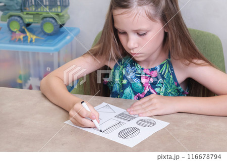 Schoolgirl draws lines with black pen. Writing practice. Childhood and activities at home. Schoolgirl draws lines with black pen. Writing practice. Childhood and activities at home. 116678794