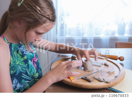 Young teenage girl molding houses out of clay. Hobbies and tools. Creativity for children, education. Young teenage girl molding houses out of clay. Hobbies and tools. Creativity for children, education. 116678833