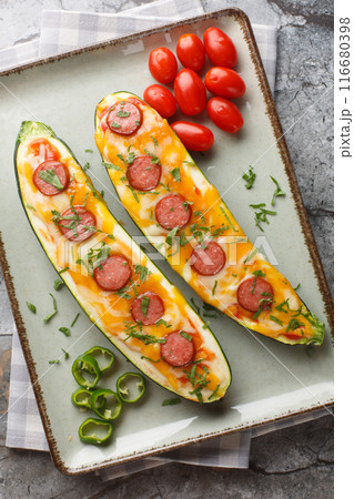Low Carb Zucchini Pizza Boats baked with cheddar and mozzarella cheese, sausages and tomato sauce close-up in a plate. Vertical top view 116680398
