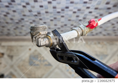 Plumber unscrews elbow adapter compression fitting nut with an adjustable wrench. 116682975