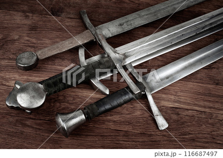 Medieval swords on wooden background. Medieval swords on wooden background. 116687497