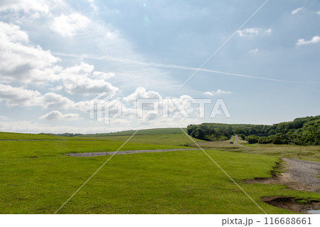 まぶしい日差しと沢山のふっくらした雲が広がる青空の下の広々としたフィールド 南ウェールズの郊外にて まぶしい日差しと沢山のふっくらした雲が広がる青空の下の広々としたフィールド 南ウェールズの郊外にて 116688661
