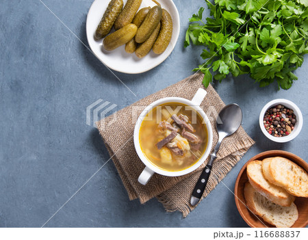 Pickle (Russian soup). Pearl soup with pickles and potatoes in a white plate on a blue background Pickle (Russian soup). Pearl soup with pickles and potatoes in a white plate on a blue background 116688837