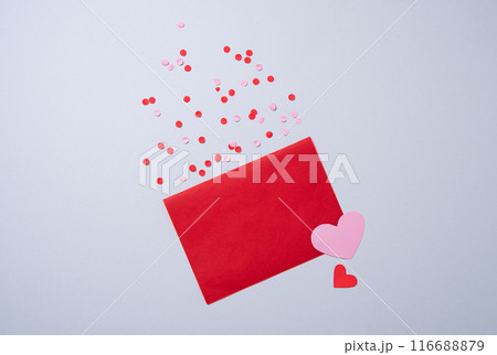 red paper envelope with free space for text with hearts and confetti on a gray background.  116688879