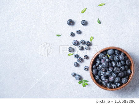 sweet fresh blueberries in a wooden  bowl  on a blue background. Top view and copy space 116688880