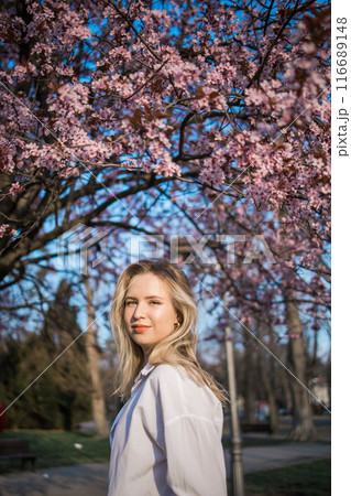 Woman with cherry flowers surrounded by blossoming trees copy space. Beauty and seasonal change and spring bloom season concept. 116689148