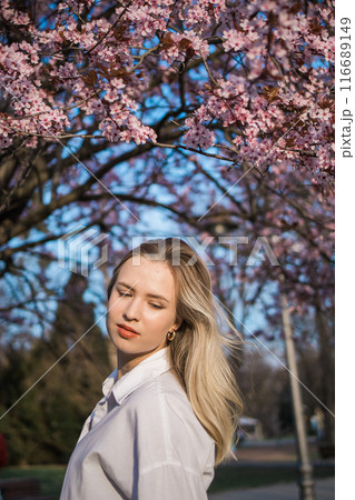 Woman with cherry flowers surrounded by blossoming trees copy space. Beauty and seasonal change and spring bloom season concept. 116689149
