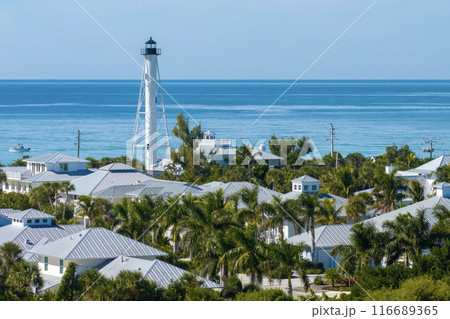 Expensive waterfront houses and white Boca Grande lighthouse on ocean shore. Small town on Gasparilla Island in southwest Florida. Premium housing development in the USA 116689365