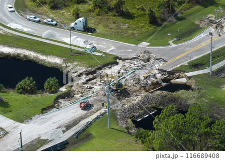 Destroyed bridge after hurricane flooding in Florida. Construction equipment at roadwork site. Reconstruction of damaged road after flood water washed away asphalt 116689408