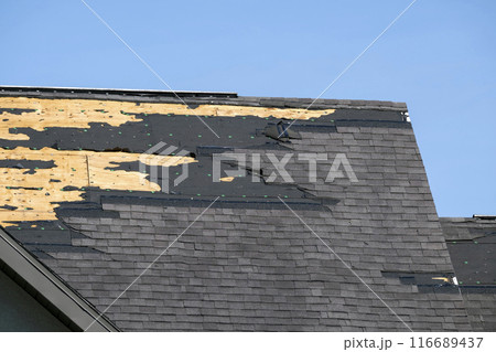 Consequences of natural disaster. Damaged house roof with missing shingles after hurricane Ian in Florida 116689437