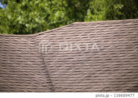 Closeup of house roof top covered with asphalt or bitumen shingles. Waterproofing of new building Closeup of house roof top covered with asphalt or bitumen shingles. Waterproofing of new building 116689477
