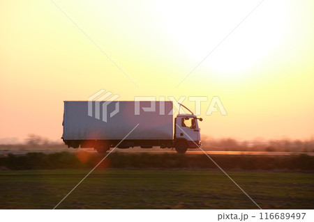 Cargo truck driving on highway hauling goods in evening. Delivery transportation and logistics concept 116689497