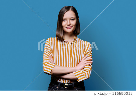 Young confident smiling woman with crossed arms on blue background Young confident smiling woman with crossed arms on blue background 116690013