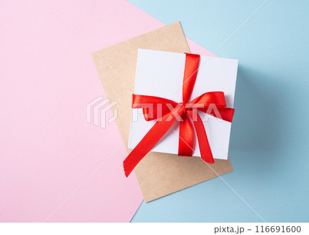 Flat lay of celebration. White gift box with red ribbon and craft envelope  116691600