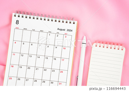 August 2024 month calendar and pen with open diary on pink fabric background. 116694443