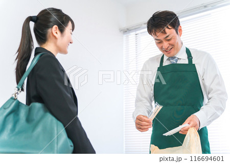レジで袋詰めをする男性コンビニスタッフと買い物客の女性(箸・おしぼり) レジで袋詰めをする男性コンビニスタッフと買い物客の女性(箸・おしぼり) 116694601
