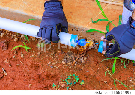 Plumber installed glues plastic PVC pipes for laying water line 116694995