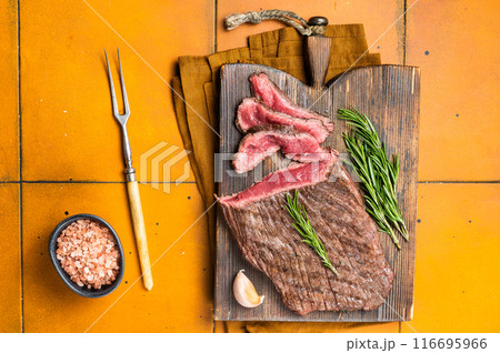 BBQ dry aged wagyu Flank Steak on a cutting board. Orange background. Top view BBQ dry aged wagyu Flank Steak on a cutting board. Orange background. Top view 116695966