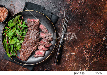 Juicy Grilled Machete skirt beef meat steak on plate with salad. Dark background. Top view. Copy space Juicy Grilled Machete skirt beef meat steak on plate with salad. Dark background. Top view. Copy space 116695979
