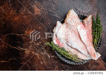 Raw ocean red perch fillet, Snapper fish with herbs. Dark background. Top view. Copy space 116695992