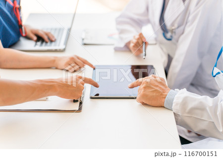 タブレットで電子カルテを見ながらカンファレンスを行う医療従事者の手元 116700151