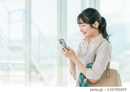 オフィスビルでスマホを使っているアジア人ビジネスウーマン オフィスビルでスマホを使っているアジア人ビジネスウーマン 116700897
