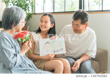 祖父母に敬老の日のお祝いに似顔絵をプレゼントする孫・女の子 116702082