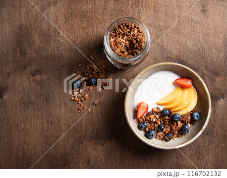 Delicious natural yogurt with homemade granola, peach and berries in a bowl  116702132