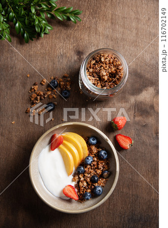 Fresh natural yogurt with homemade granola, peach, strawberry and blueberry in a bowl Fresh natural yogurt with homemade granola, peach, strawberry and blueberry in a bowl 116702149