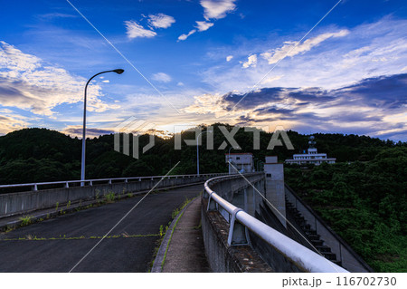 2024年夏布目ダムの夕景　堰堤の向こうで黄金色に染まり始めた夕焼け空 116702730