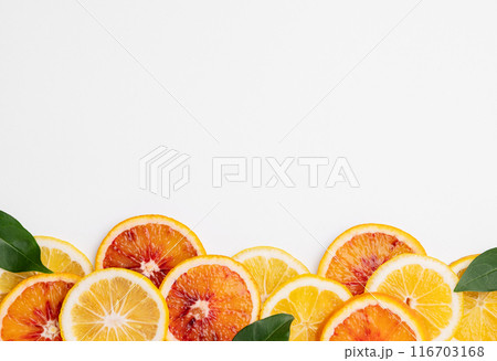Juicy slices of lemons, blood oranges and leaves on a light isolated background. Juicy slices of lemons, blood oranges and leaves on a light isolated background. 116703168