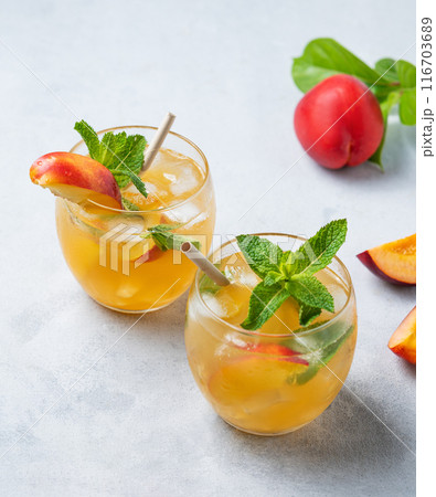 Two glasses with peach cocktail, lemonade or iced tea on a light background. 116703689