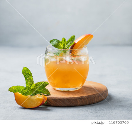 Refreshing peach cocktail, lemonade or iced tea on a wooden board on a light background. Refreshing peach cocktail, lemonade or iced tea on a wooden board on a light background. 116703709