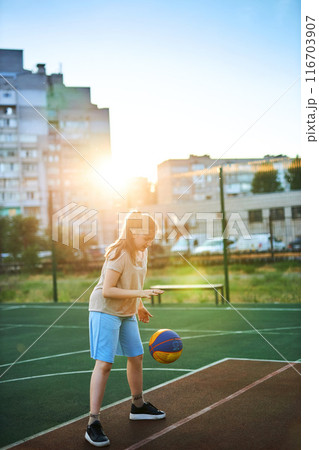 caucasian little basketball player jumps to throw the ball into the basket hoop 116703907