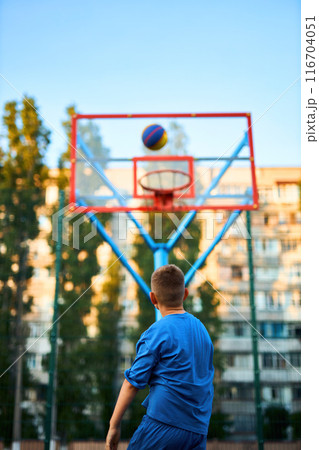 caucasian little basketball player jumps to throw the ball into the basket hoop caucasian little basketball player jumps to throw the ball into the basket hoop 116704051