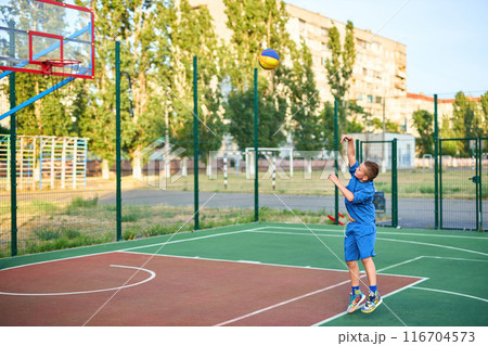 caucasian little basketball player jumps to throw the ball into the basket hoop 116704573
