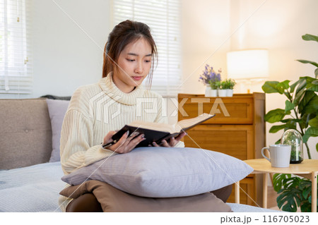 Young woman sitting and reading a book from the couch. Young woman sitting and reading a book from the couch. 116705023