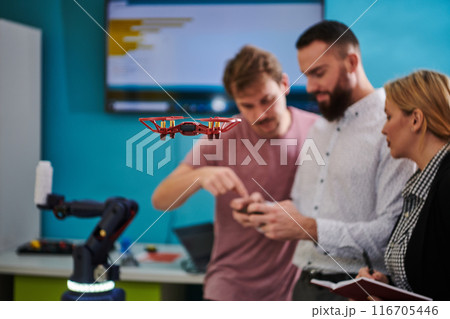 A group of students working together in a laboratory, dedicated to exploring the aerodynamic capabilities of a drone 116705446