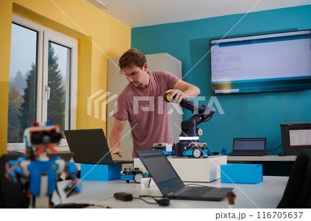 A student testing his new invention of a robotic arm in the laboratory, showcasing the culmination of his research and technological prowess. 116705637