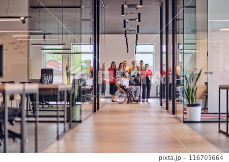 A diverse group of young business people congregates within a modern startup's glass-enclosed office, featuring inclusivity with a person in a wheelchair, an African American young man , and a hijab A diverse group of young business people congregates within a modern startup's glass-enclosed office, featuring inclusivity with a person in a wheelchair, an African American young man , and a hijab 116705664