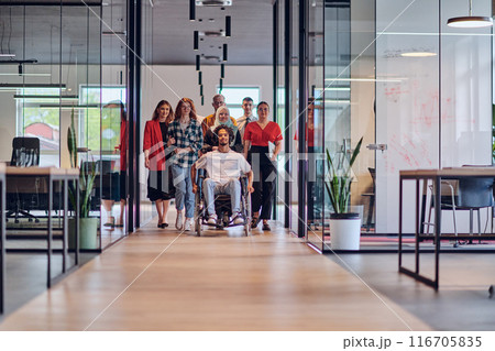 A diverse group of young business people congregates within a modern startup's glass-enclosed office, featuring inclusivity with a person in a wheelchair, an African American young man , and a hijab A diverse group of young business people congregates within a modern startup's glass-enclosed office, featuring inclusivity with a person in a wheelchair, an African American young man , and a hijab 116705835