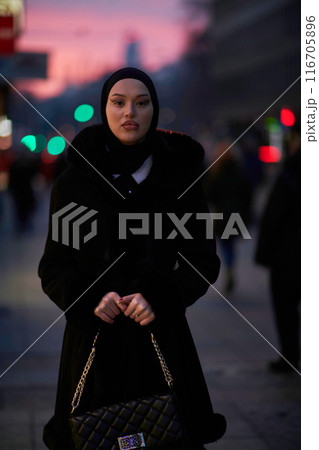 Muslim woman walking on an urban city street on a cold winter night wearing hijab 116705896