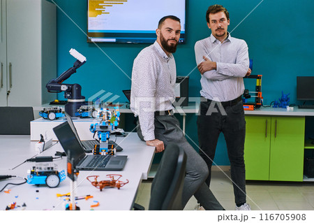 A group of colleagues collaborate in a lab while testing a 3D printer, demonstrating their commitment to technological advancement and scientific research. 116705908
